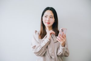 スマホを手にして考える女性